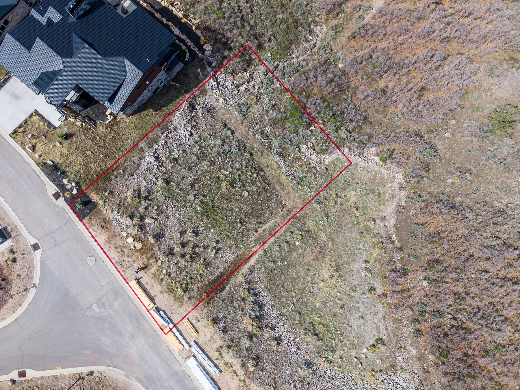 Overhead aerial view of 11461 N White Tail Court lot boundary with red lines and neighboring completed home, Soaring Hawk Hideout Utah