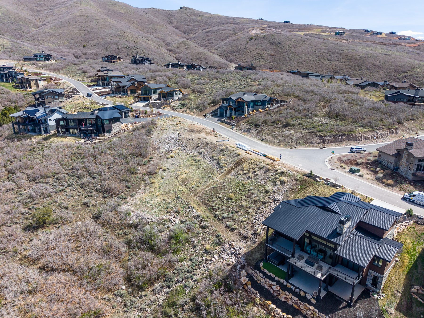 Aerial view of 11461 N White Tail Court beside completed Soaring Hawk mountain modern home with walk-out lower level deck and outdoor living